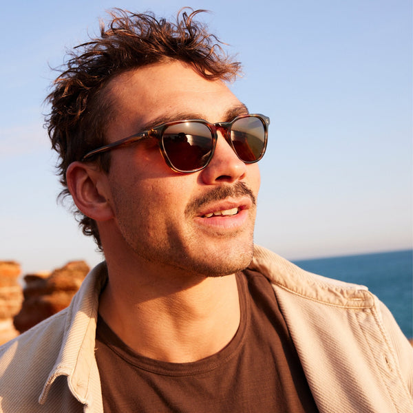 Man smiling look our to the distance wearing mineral glass sunglasses