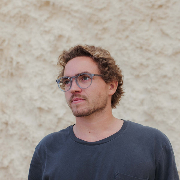 Man wearing dark grey shirt and wearing glasses looking out