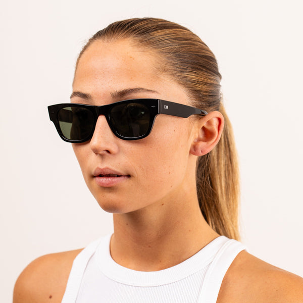 Blonde woman studio head shot wearing black wayfarer sunglasses